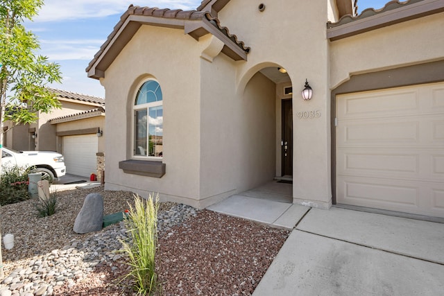 9035 S Sky St NW, Albuquerque, NM 87114 - view of exterior entry featuring stucco siding, a tiled roof, and an attached garage