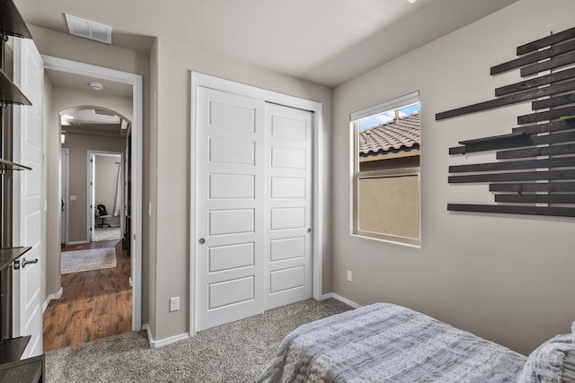 9035 S Sky St NW, Albuquerque, NM 87114 - bedroom featuring arched walkways, baseboards, a closet, and dark colored carpet