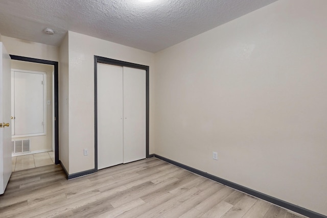 2815 Quail Pointe Dr NW, Albuquerque, NM 87120 - unfurnished bedroom with light wood-type flooring, a textured ceiling, baseboards, and a closet