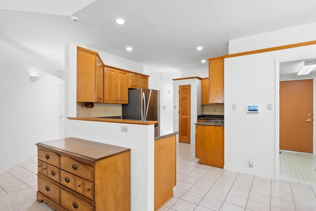 7913 Woodridge Dr NE, Albuquerque, NM 87109 - kitchen featuring freestanding refrigerator, dark countertops, light tile patterned floors, recessed lighting, and brown cabinets