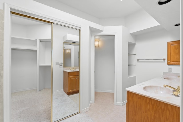 7913 Woodridge Dr NE, Albuquerque, NM 87109 - full bath featuring double vanity, a walk in closet, baseboards, and tile patterned flooring
