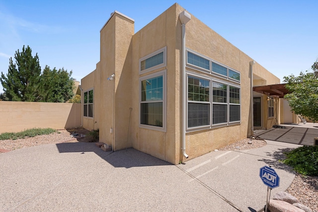 7913 Woodridge Dr NE, Albuquerque, NM 87109 - view of side of home with stucco siding and a patio area