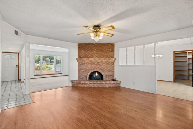 7401 Volunteer St NE, Albuquerque, NM 87109 - unfurnished living room with wood finished floors, ceiling fan, a textured ceiling, a fireplace, and a chandelier