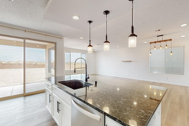 3034 Shannon Ln NE, Rio Rancho, NM 87144 - kitchen featuring stainless steel dishwasher, a sink, light wood-style floors, a textured ceiling, and a kitchen island with sink