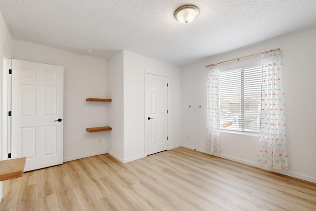 3034 Shannon Ln NE, Rio Rancho, NM 87144 - unfurnished bedroom with light wood-style floors, a textured ceiling, multiple windows, and baseboards