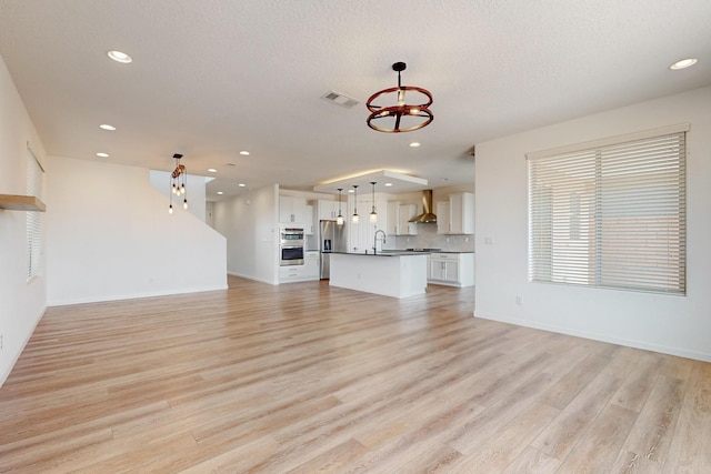 3034 Shannon Ln NE, Rio Rancho, NM 87144 - unfurnished living room with a sink, a chandelier, light wood finished floors, recessed lighting, and a textured ceiling