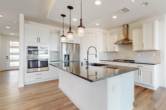3034 Shannon Ln NE, Rio Rancho, NM 87144 - kitchen with appliances with stainless steel finishes, wall chimney exhaust hood, a sink, light wood-style floors, and white cabinetry