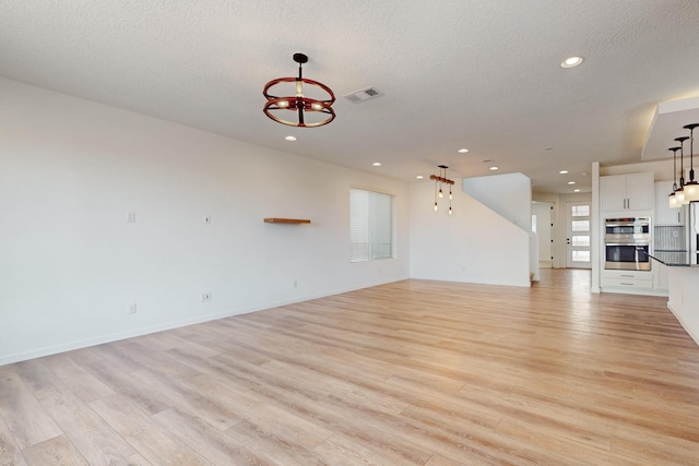 3034 Shannon Ln NE, Rio Rancho, NM 87144 - unfurnished living room with a chandelier, light wood-style floors, a textured ceiling, and recessed lighting