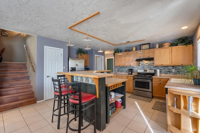 6308 Turquoise Trl NE, Rio Rancho, NM 87144 - kitchen with stainless steel appliances, light tile patterned floors, under cabinet range hood, open shelves, and a textured ceiling