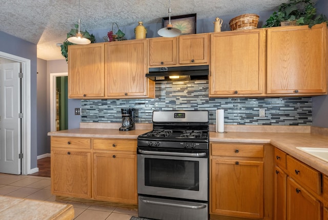 6308 Turquoise Trl NE, Rio Rancho, NM 87144 - kitchen featuring under cabinet range hood, stainless steel gas range oven, decorative backsplash, light countertops, and light tile patterned floors