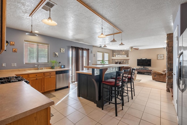 6308 Turquoise Trl NE, Rio Rancho, NM 87144 - kitchen featuring stainless steel dishwasher, a stone fireplace, ceiling fan, open floor plan, and a breakfast bar area