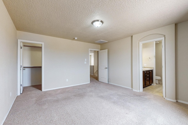 221 Landing Trl, Rio Rancho, NM 87124 - unfurnished bedroom featuring light colored carpet, a textured ceiling, ensuite bathroom, baseboards, and a spacious closet