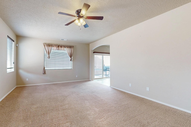 221 Landing Trl, Rio Rancho, NM 87124 - spare room with a textured ceiling, carpet, arched walkways, ceiling fan, and plenty of natural light