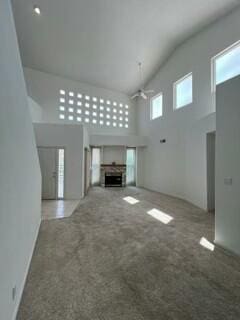 620 Renaissance Loop SE, Rio Rancho, NM 87124 - unfurnished living room with high vaulted ceiling, a ceiling fan, carpet floors, and a fireplace