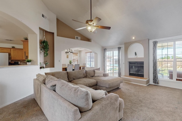 1034 Wagon Trail St, Los Lunas, NM 87031 - living room with arched walkways, light colored carpet, ceiling fan, high vaulted ceiling, and a glass covered fireplace