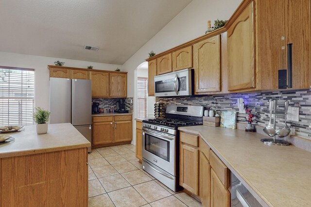 1034 Wagon Trail St, Los Lunas, NM 87031 - kitchen featuring stainless steel appliances, tasteful backsplash, vaulted ceiling, healthy amount of natural light, and light countertops