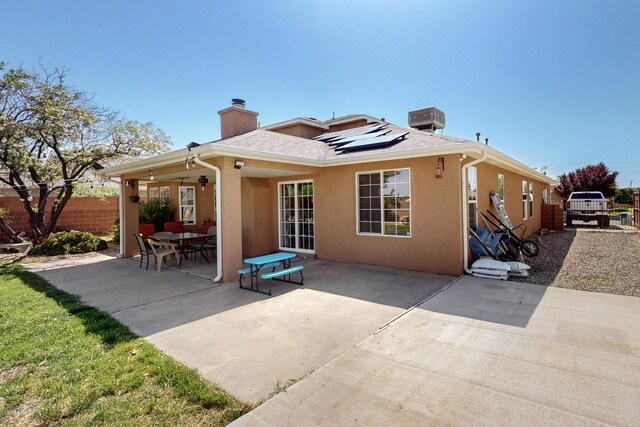 1034 Wagon Trail St, Los Lunas, NM 87031 - back of house featuring a chimney, solar panels, stucco siding, a patio, and a shingled roof