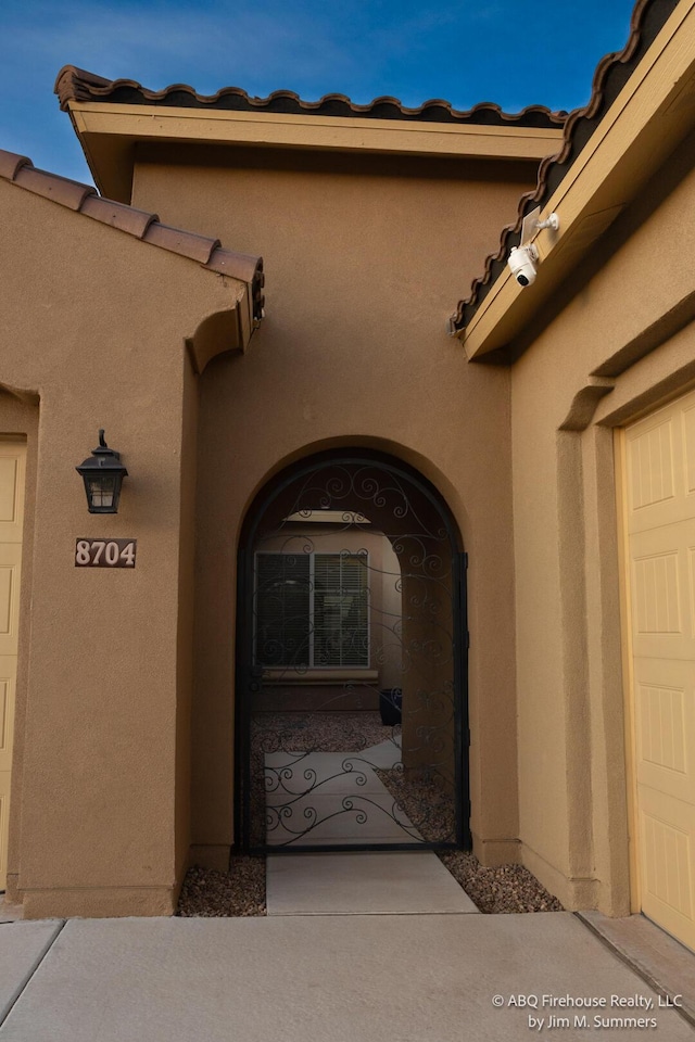8704 Espacio Verde Rd, Albuquerque, NM 87120 - view of exterior entry featuring stucco siding and a tile roof