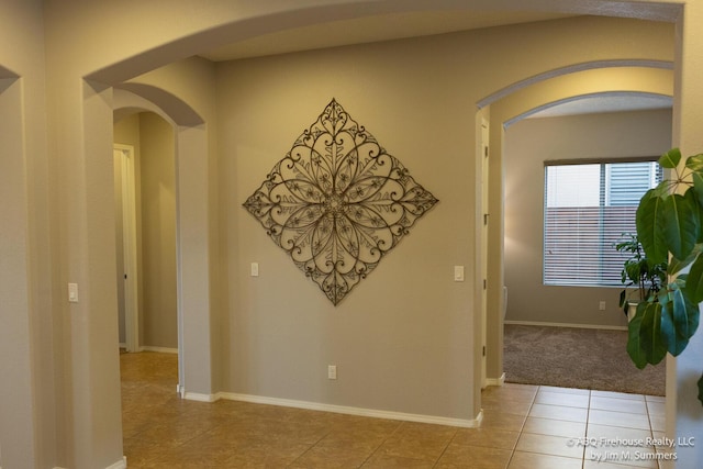 8704 Espacio Verde Rd, Albuquerque, NM 87120 - corridor with arched walkways, light tile patterned flooring, and baseboards