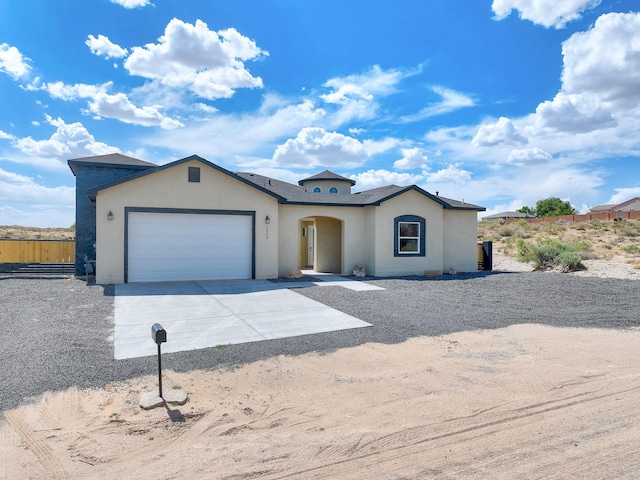 1209 11th St SE, Rio Rancho, NM 87124 - view of front facade with an attached garage, driveway, and stucco siding
