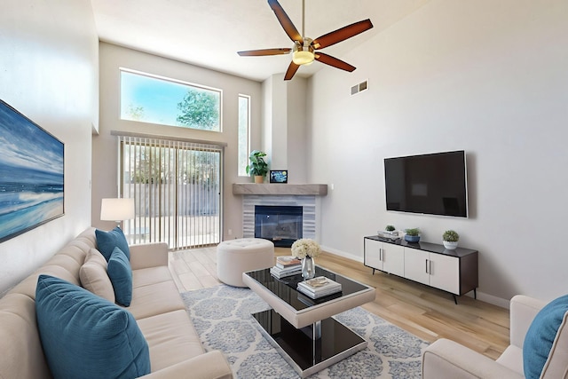 10809 Academy Ridge Rd NE, Albuquerque, NM 87111 - living area featuring a high ceiling, wood finished floors, a ceiling fan, a glass covered fireplace, and baseboards