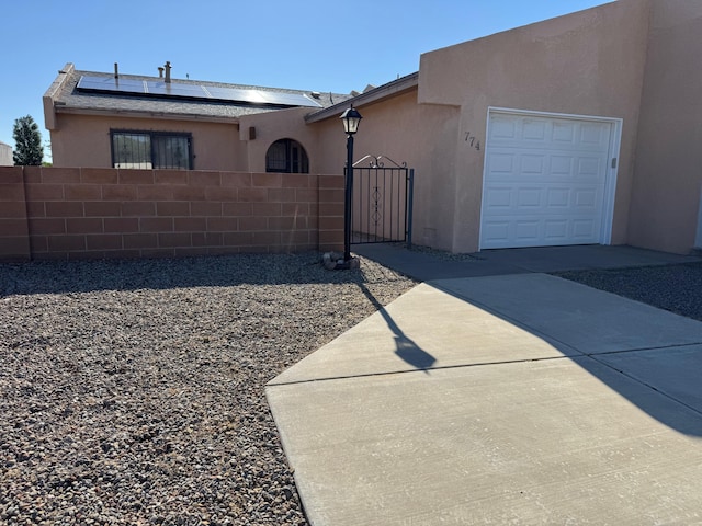 774 Stallion Rd SE, Rio Rancho, NM 87124 - view of front of home with stucco siding, a garage, solar panels, a gate, and concrete driveway