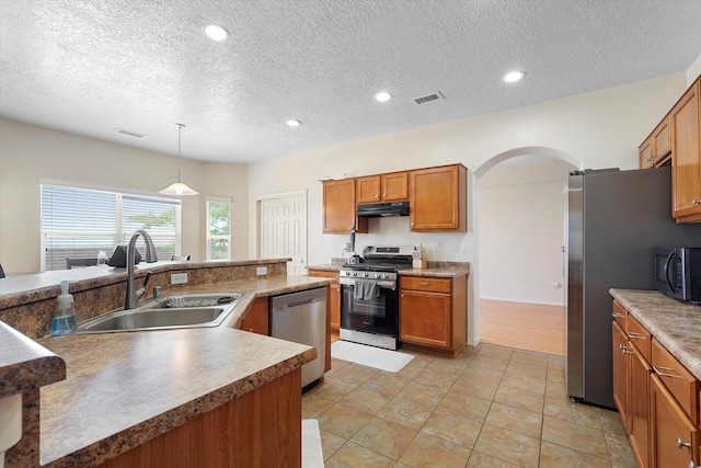 1311 Mirador Loop NE, Rio Rancho, NM 87144 - kitchen with stainless steel appliances, a sink, under cabinet range hood, arched walkways, and brown cabinetry