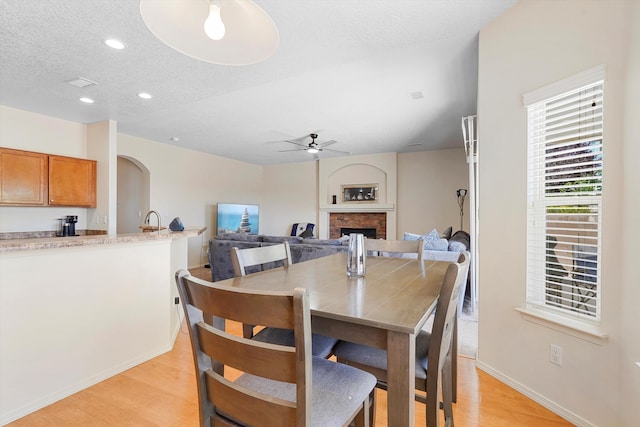 1311 Mirador Loop NE, Rio Rancho, NM 87144 - dining area with ceiling fan, a fireplace, light wood finished floors, baseboards, and a textured ceiling