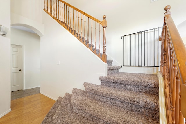 1311 Mirador Loop NE, Rio Rancho, NM 87144 - staircase featuring arched walkways, wood finished floors, baseboards, and a towering ceiling
