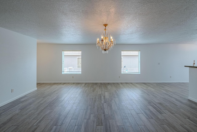 3742 Cattle Dr, Rio Rancho, NM 87144 - unfurnished room featuring healthy amount of natural light, wood finished floors, a chandelier, and a textured ceiling