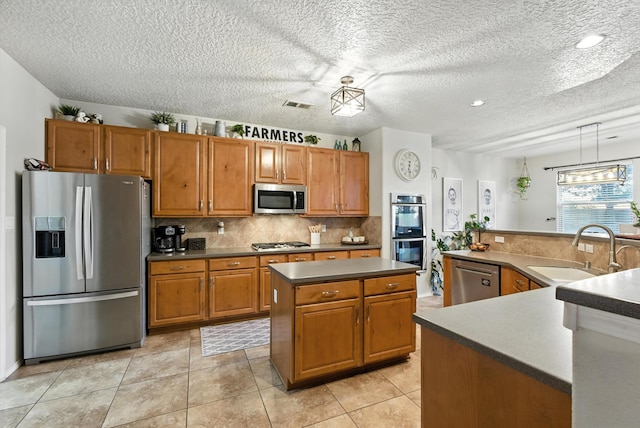 2004 Rancho Oro Ave SE, Rio Rancho, NM 87124 - kitchen featuring stainless steel appliances, a kitchen island, brown cabinetry, decorative backsplash, and a textured ceiling