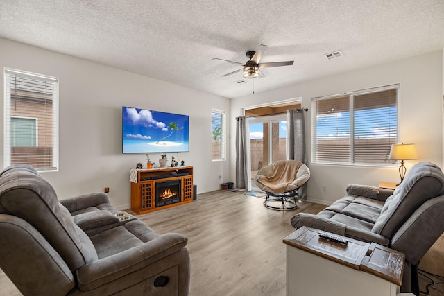 240 Rio Chama Cir SW, Los Lunas, NM 87031 - living room with a ceiling fan, a textured ceiling, wood finished floors, baseboards, and a warm lit fireplace