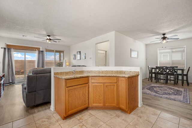 240 Rio Chama Cir SW, Los Lunas, NM 87031 - kitchen with a ceiling fan, open floor plan, a textured ceiling, and light stone countertops