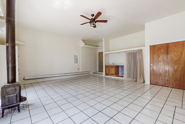 41 El Rancho Grande Rd, Mcintosh, NM 87032 - unfurnished living room featuring baseboard heating, a ceiling fan, a wood stove, light tile patterned flooring, and electric panel