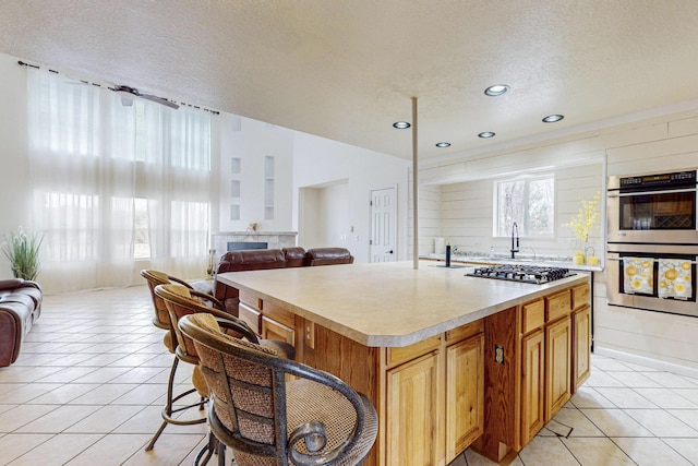 41 El Rancho Grande Rd, Mcintosh, NM 87032 - kitchen featuring appliances with stainless steel finishes, a textured ceiling, light countertops, light tile patterned flooring, and a center island