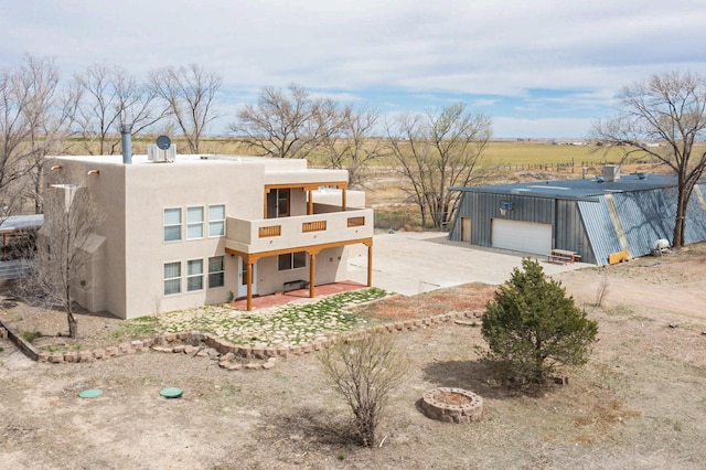 41 El Rancho Grande Rd, Mcintosh, NM 87032 - rear view of house with an outbuilding, concrete driveway, a detached garage, a balcony, and stucco siding