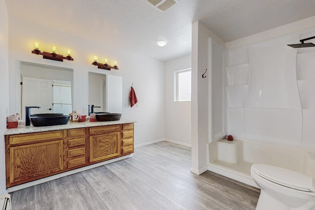 41 El Rancho Grande Rd, Mcintosh, NM 87032 - bathroom with double vanity, wood finished floors, a baseboard radiator, a shower, and a textured ceiling
