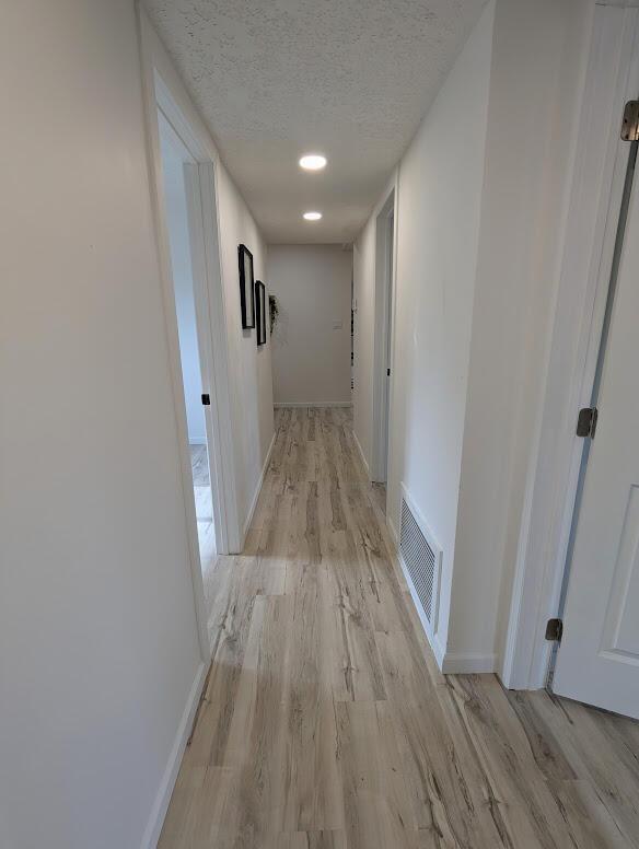2824 Texas St NE, Albuquerque, NM 87110 - hallway with light wood-style floors, a textured ceiling, and baseboards