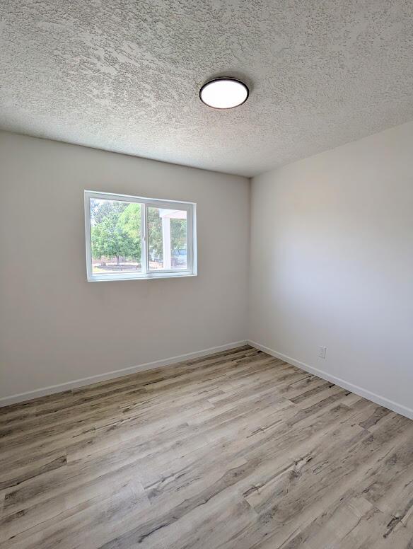 2824 Texas St NE, Albuquerque, NM 87110 - unfurnished room featuring wood finished floors, a textured ceiling, and baseboards