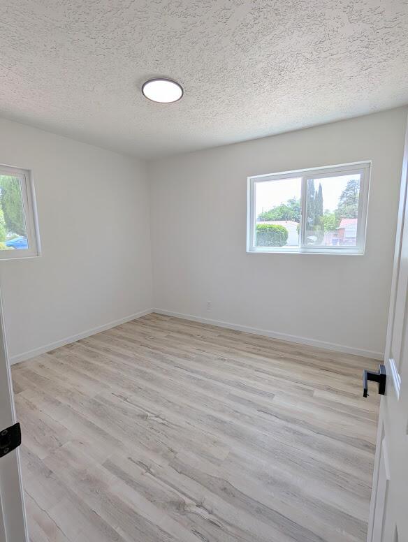 2824 Texas St NE, Albuquerque, NM 87110 - spare room with a textured ceiling, light wood-type flooring, and baseboards