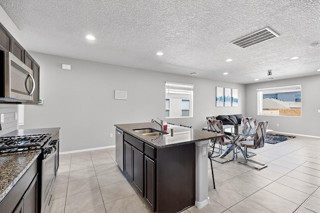 4871 Longs Peak Rd NE, Rio Rancho, NM 87144 - kitchen with stainless steel appliances, a sink, dark stone countertops, light tile patterned floors, and open floor plan