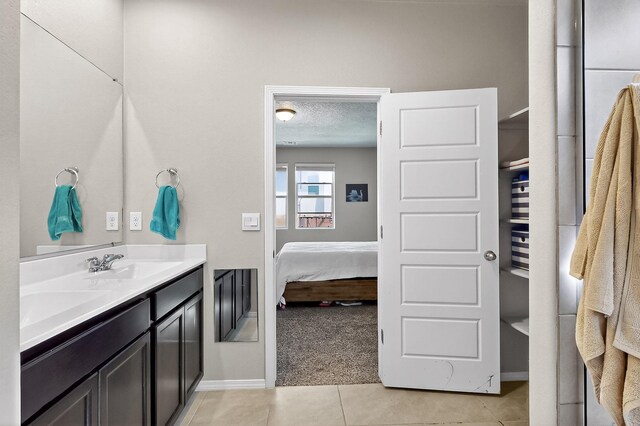 4871 Longs Peak Rd NE, Rio Rancho, NM 87144 - full bathroom with double vanity, tile patterned floors, baseboards, ensuite bath, and a textured ceiling