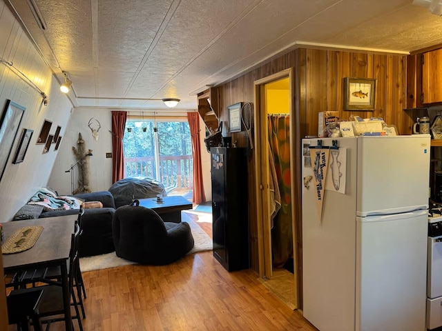 123 Pine Dr, Jemez Springs, NM 87025 - kitchen with freestanding refrigerator, light wood-style flooring, wood walls, and a textured ceiling