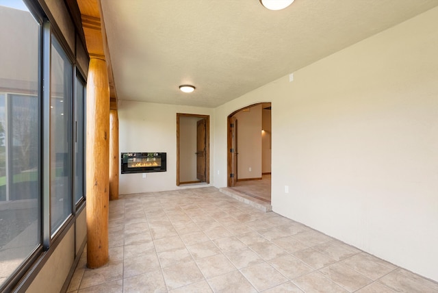 98 Edgewood Unit 7, Edgewood, NM 87015 - empty room with arched walkways, light tile patterned flooring, heating unit, and a textured ceiling
