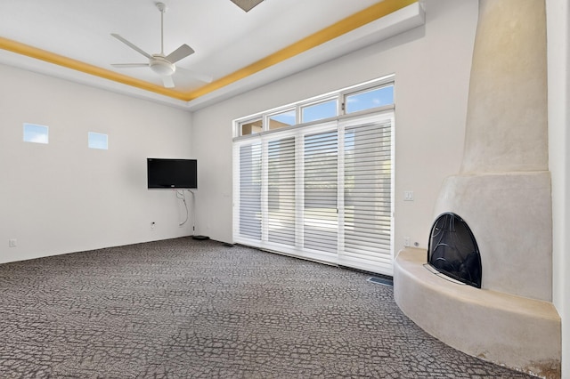 2600 Griegos Pl NW, Albuquerque, NM 87107 - unfurnished living room with a ceiling fan, carpet floors, a tray ceiling, and a fireplace with raised hearth