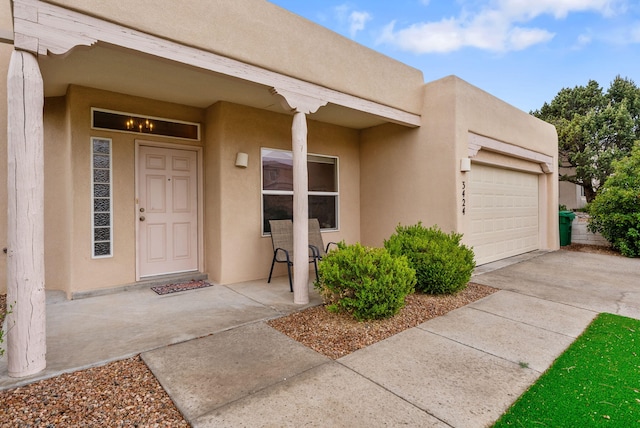 3424 Calle Suenos SE, Rio Rancho, NM 87124 - doorway to property featuring an attached garage, stucco siding, and driveway