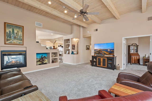 3424 Calle Suenos SE, Rio Rancho, NM 87124 - living room featuring a wood ceiling with exposed beams, carpet, a multi sided fireplace, a ceiling fan, and built in shelves