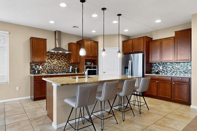 2927 Kings Canyon Loop NE, Rio Rancho, NM 87144 - kitchen with wall chimney exhaust hood, appliances with stainless steel finishes, backsplash, brown cabinetry, and a textured ceiling