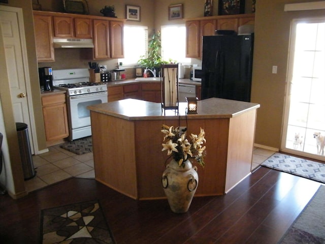 4608 Stafford Pl NW, Albuquerque, NM 87120 - kitchen featuring white range with gas cooktop, under cabinet range hood, freestanding refrigerator, a sink, and wood finished floors