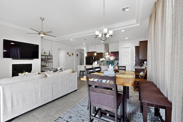 6854 Cleary Loop NE, Rio Rancho, NM 87144 - dining room with arched walkways, a chandelier, a raised ceiling, recessed lighting, and a glass covered fireplace